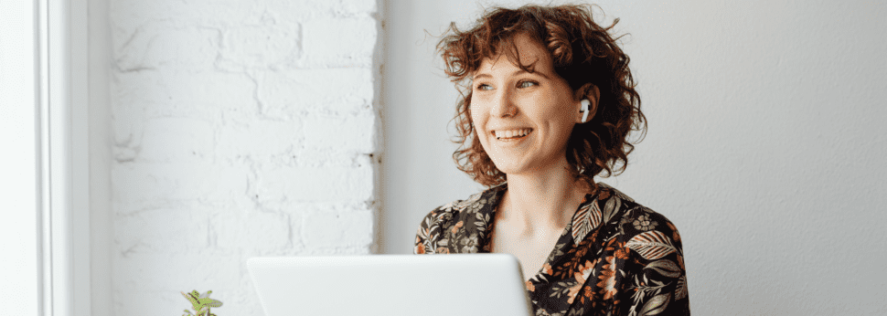 Smiling woman using a laptop with benefits administration software.
