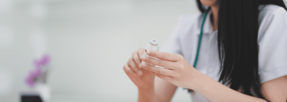 An image of a medical worker holding a small vial.